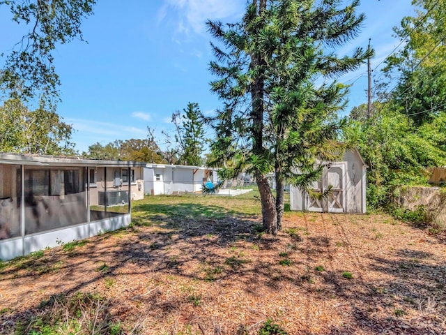 view of yard featuring fence, an outdoor structure, a shed, and a sunroom