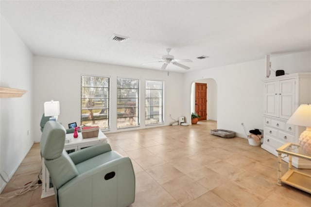 living area with visible vents, arched walkways, and a ceiling fan