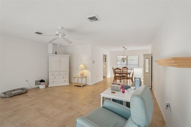 living area featuring visible vents and ceiling fan with notable chandelier