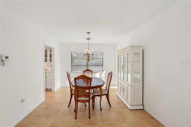 dining area with a notable chandelier, light tile patterned flooring, and baseboards