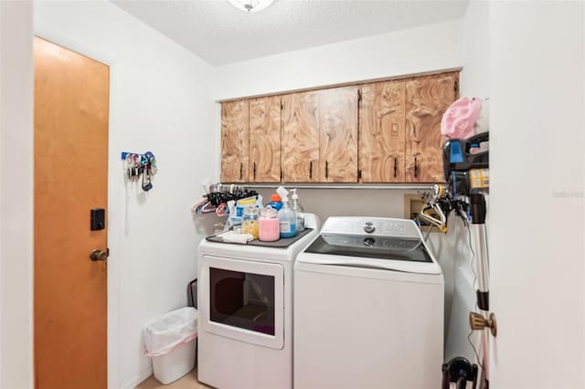 laundry room featuring cabinet space, a textured ceiling, and independent washer and dryer