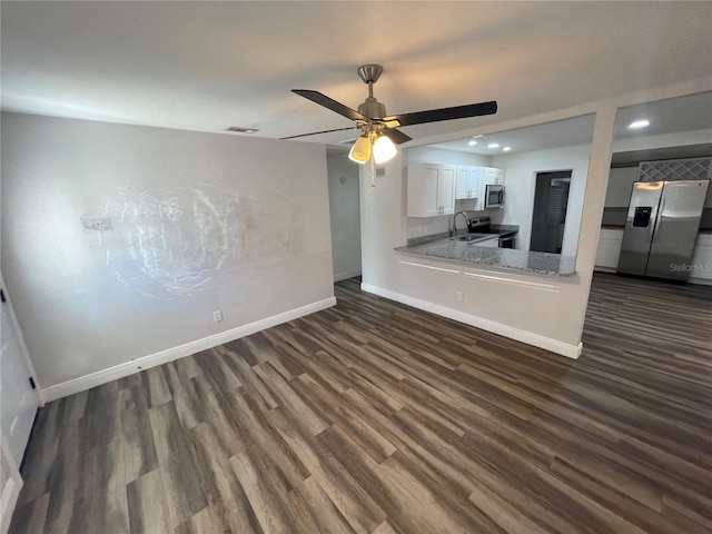 unfurnished living room with visible vents, dark wood-type flooring, a sink, baseboards, and ceiling fan