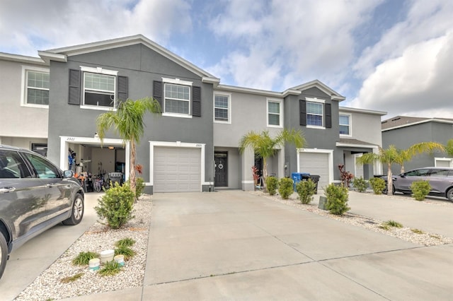 multi unit property featuring an attached garage, driveway, and stucco siding