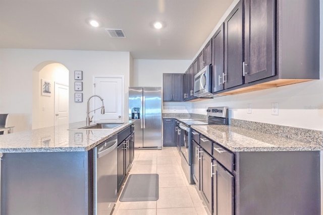 kitchen with visible vents, a sink, stainless steel appliances, arched walkways, and light tile patterned floors