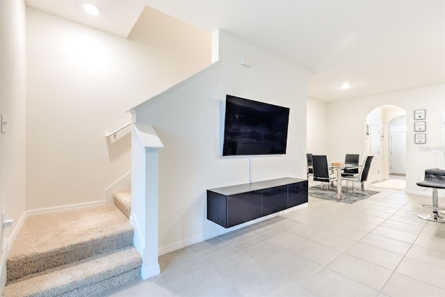 living room with stairway, light tile patterned flooring, recessed lighting, and arched walkways