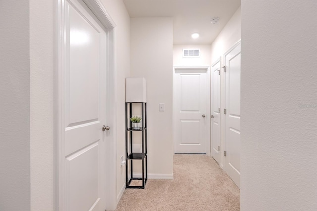 corridor featuring light carpet, visible vents, and baseboards