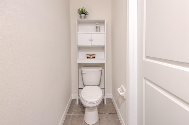 bathroom with baseboards, toilet, and tile patterned flooring