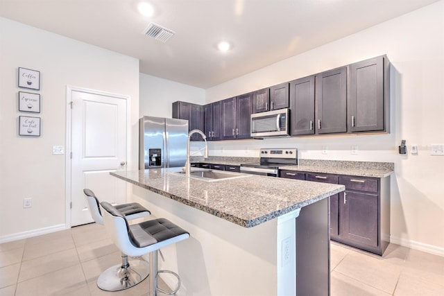 kitchen with a kitchen bar, light tile patterned floors, visible vents, and appliances with stainless steel finishes