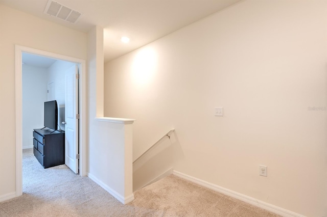 hallway featuring an upstairs landing, visible vents, baseboards, and carpet