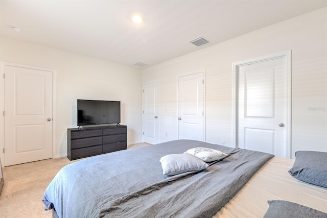 bedroom with visible vents, light carpet, and baseboards