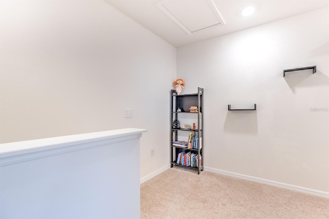 interior space with light carpet, attic access, and baseboards