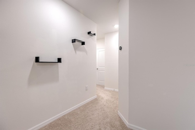 hallway featuring baseboards and light colored carpet