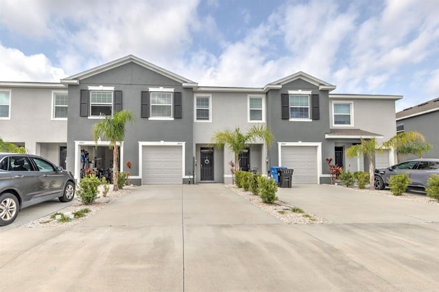 townhome / multi-family property featuring stucco siding, driveway, and a garage