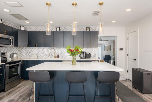 kitchen featuring visible vents, appliances with stainless steel finishes, a breakfast bar area, and light countertops