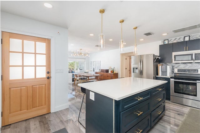 kitchen with light wood finished floors, visible vents, a kitchen island, light countertops, and appliances with stainless steel finishes