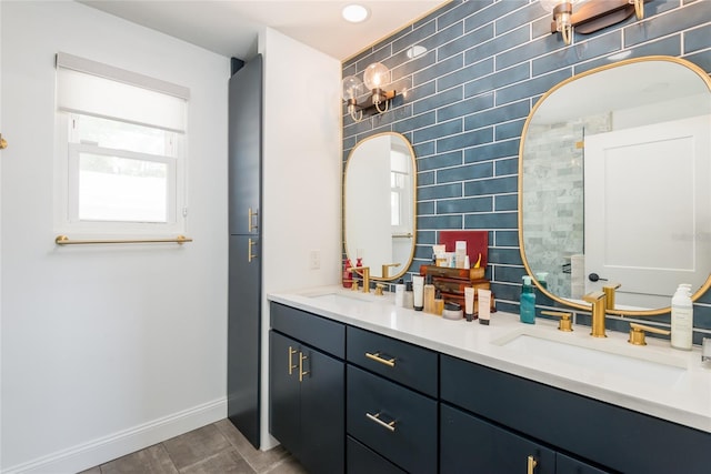 full bathroom featuring double vanity, backsplash, baseboards, and a sink