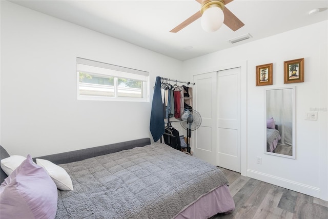 bedroom featuring visible vents, ceiling fan, baseboards, wood finished floors, and a closet