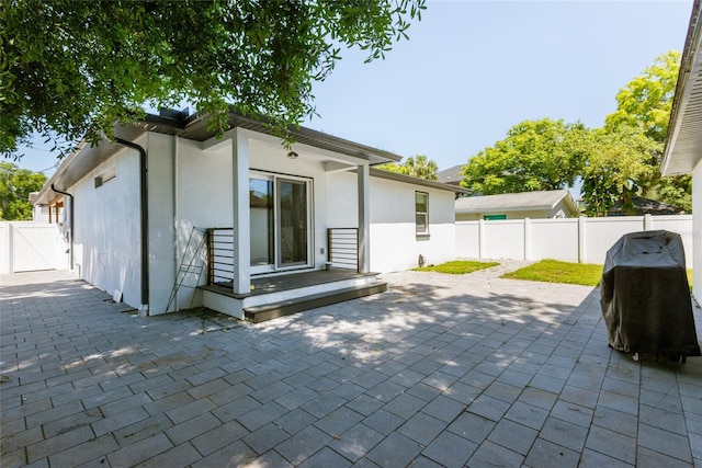 back of property featuring a fenced backyard, stucco siding, a patio, and a gate