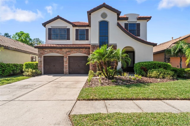 mediterranean / spanish-style house featuring stucco siding, stone siding, a garage, and concrete driveway