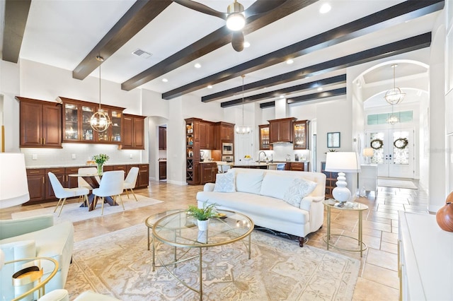 living area featuring arched walkways, a chandelier, french doors, and visible vents