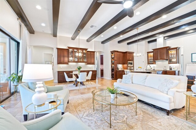 living area with beam ceiling, ceiling fan with notable chandelier, and arched walkways