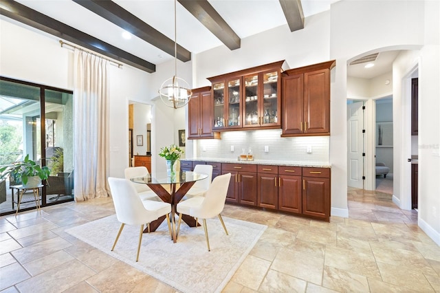 dining room featuring visible vents, beam ceiling, arched walkways, baseboards, and a towering ceiling