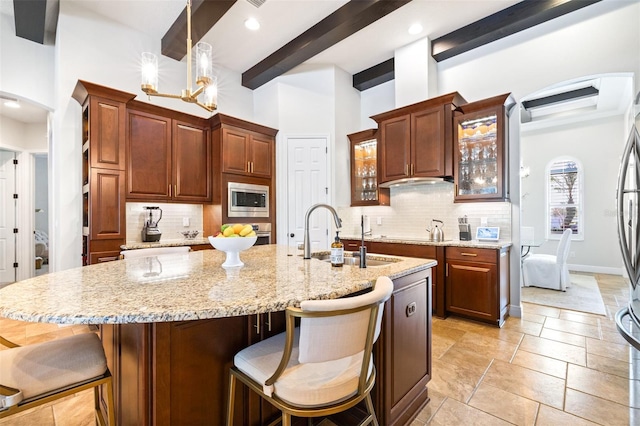 kitchen featuring beam ceiling, a sink, stainless steel microwave, a kitchen breakfast bar, and glass insert cabinets