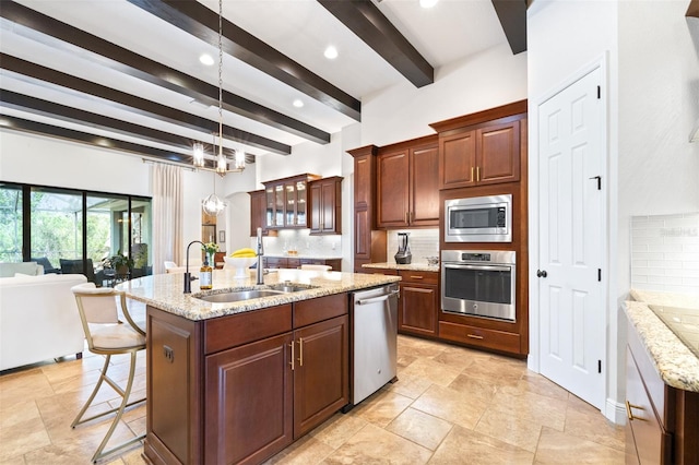 kitchen with a sink, stainless steel appliances, backsplash, and a kitchen island with sink