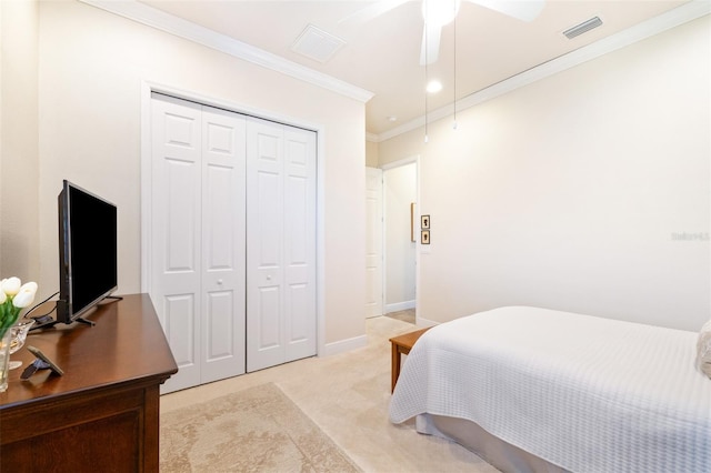 bedroom with visible vents, crown molding, baseboards, light carpet, and a closet