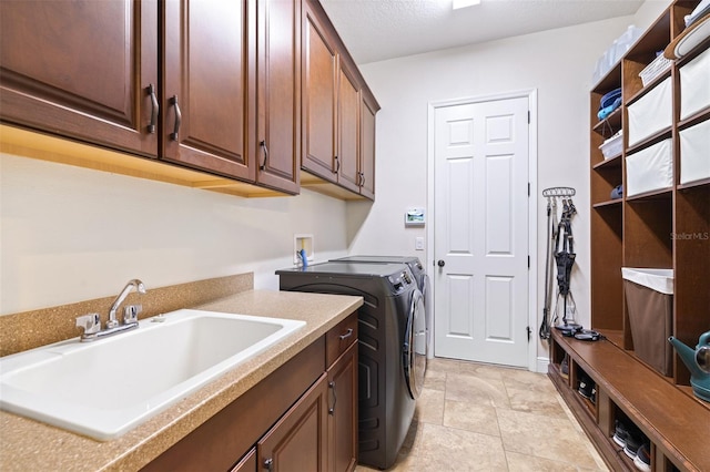 laundry room featuring washer and clothes dryer, cabinet space, a textured ceiling, and a sink