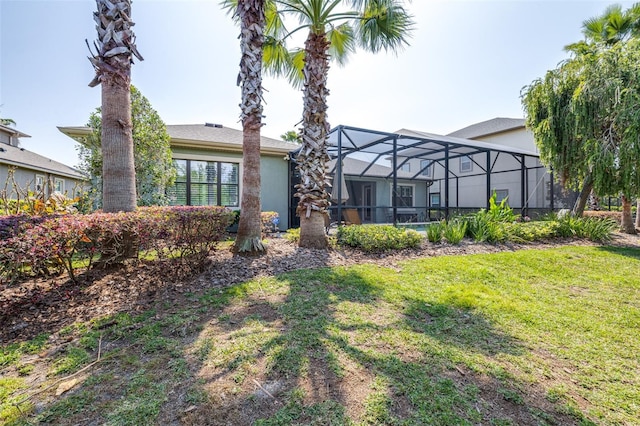 rear view of property featuring a lanai, stucco siding, and a yard