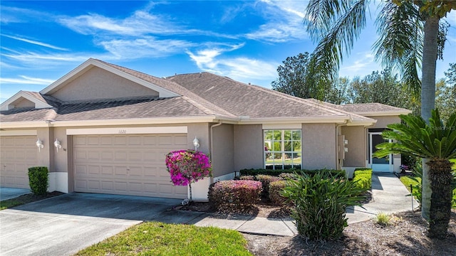 single story home with an attached garage, driveway, roof with shingles, and stucco siding