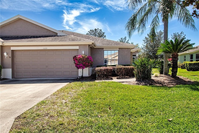 ranch-style home with a front yard, roof with shingles, an attached garage, stucco siding, and concrete driveway