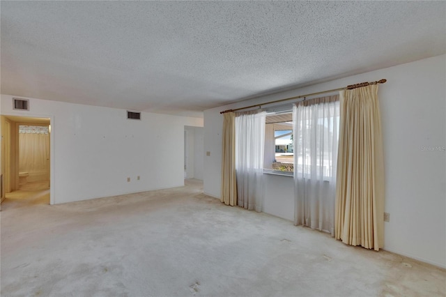 carpeted spare room featuring a textured ceiling and visible vents