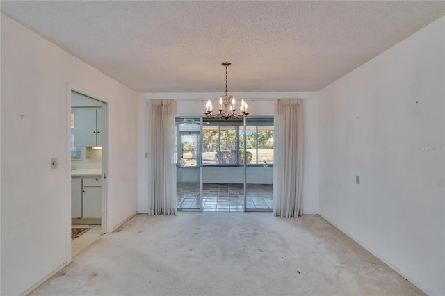 unfurnished dining area with a textured ceiling, carpet, and a chandelier