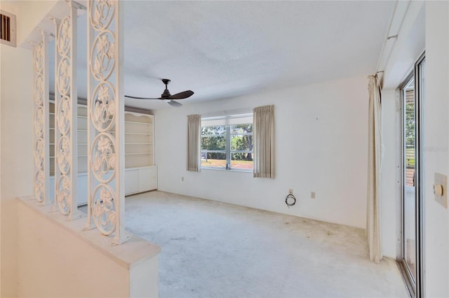 carpeted spare room featuring a textured ceiling, ceiling fan, and visible vents