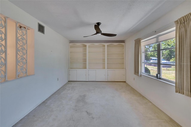 unfurnished room with carpet flooring, a textured ceiling, visible vents, ceiling fan, and built in features