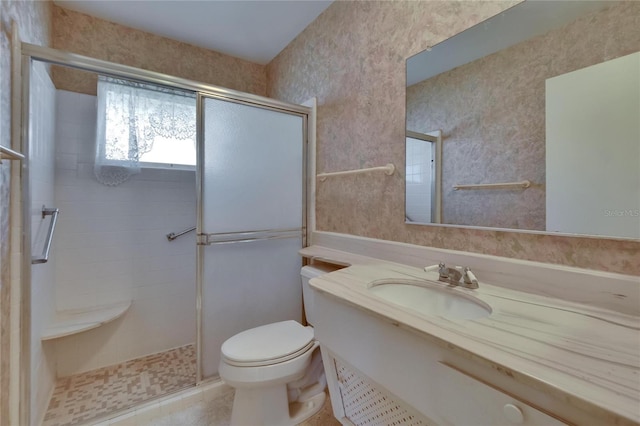 bathroom with a shower with shower door, toilet, wallpapered walls, vanity, and tile patterned flooring