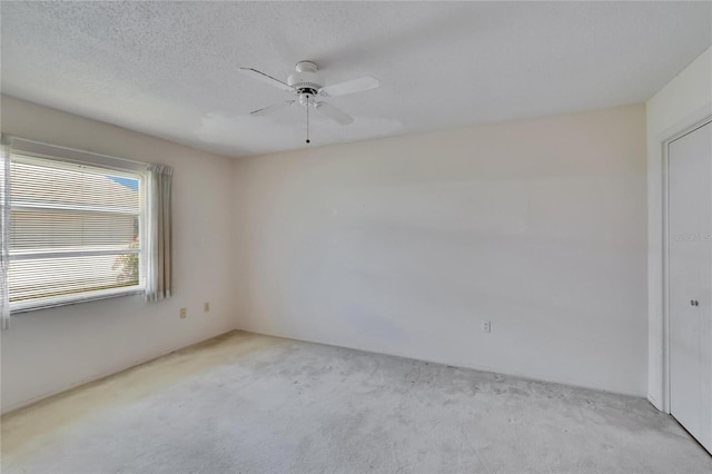 carpeted empty room featuring a textured ceiling and ceiling fan