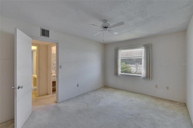 carpeted empty room with a textured ceiling, ceiling fan, and visible vents
