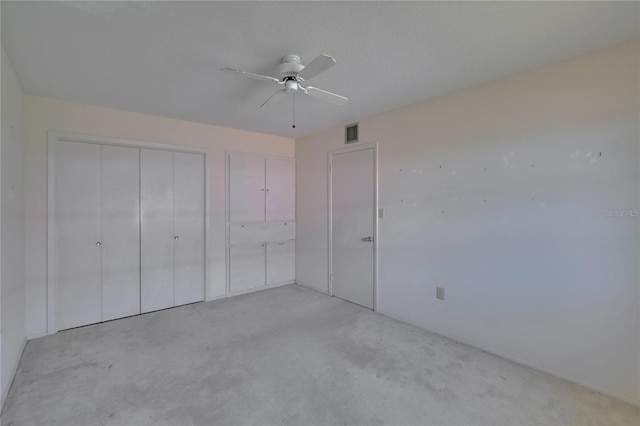 unfurnished bedroom with light colored carpet, visible vents, and a ceiling fan
