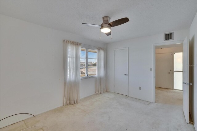 unfurnished bedroom featuring carpet flooring, a textured ceiling, ceiling fan, and visible vents