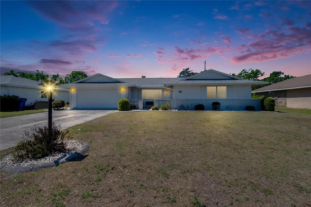 ranch-style home featuring brick siding, a lawn, a garage, and driveway