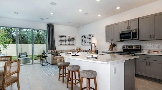 kitchen with gray cabinetry, open floor plan, light countertops, appliances with stainless steel finishes, and a sink