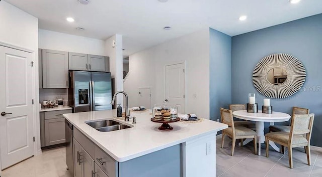 kitchen featuring gray cabinetry, dishwasher, stainless steel refrigerator with ice dispenser, and a sink