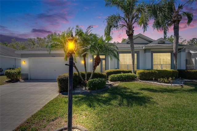single story home with a garage, stucco siding, driveway, and a yard