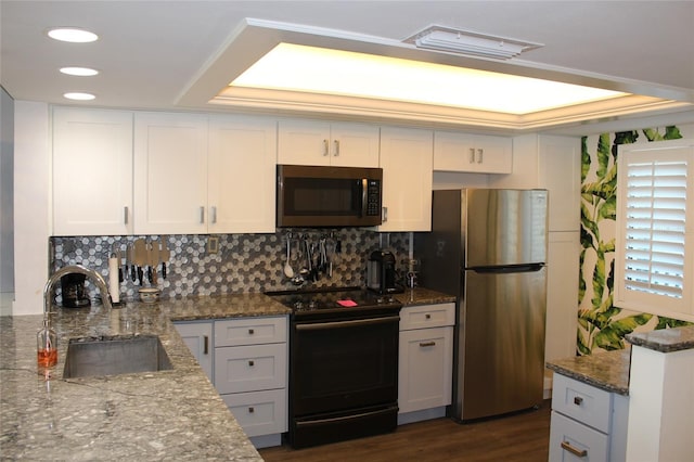 kitchen with a sink, backsplash, stainless steel appliances, dark stone counters, and dark wood-style flooring