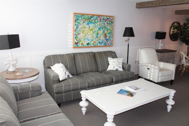 living area featuring beam ceiling, wainscoting, and a decorative wall