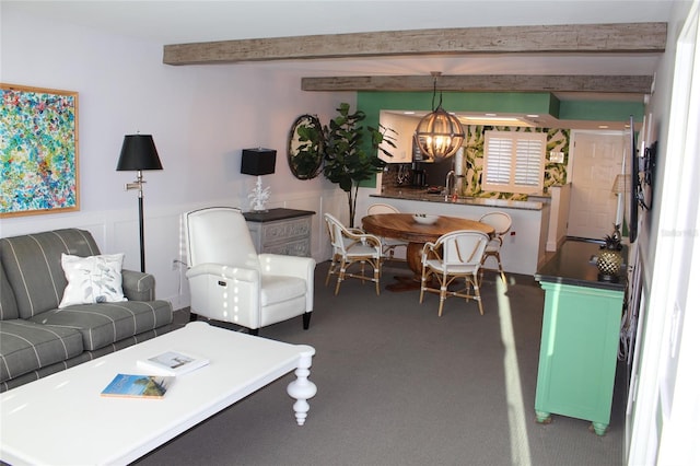 living area with a wainscoted wall, beam ceiling, carpet floors, and an inviting chandelier