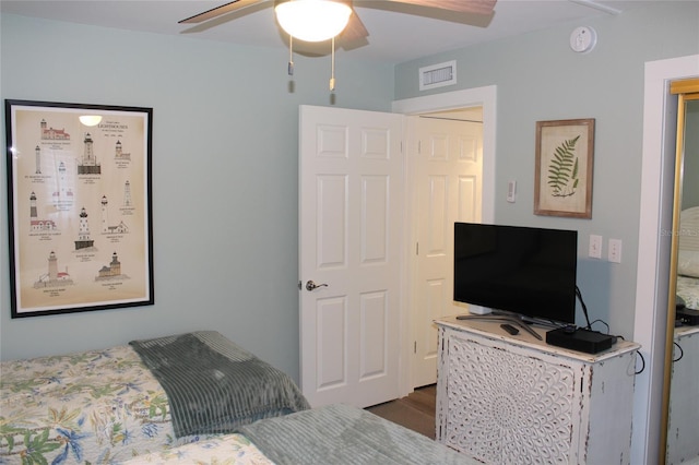 bedroom with wood finished floors, visible vents, and ceiling fan